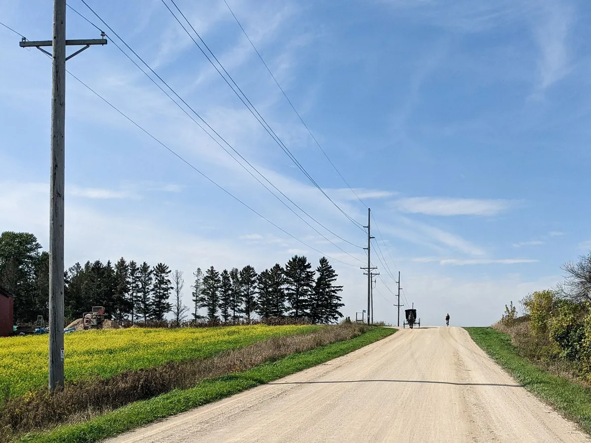 Unpaved rural road in Amish country with a horse-drawn buggy in the distance