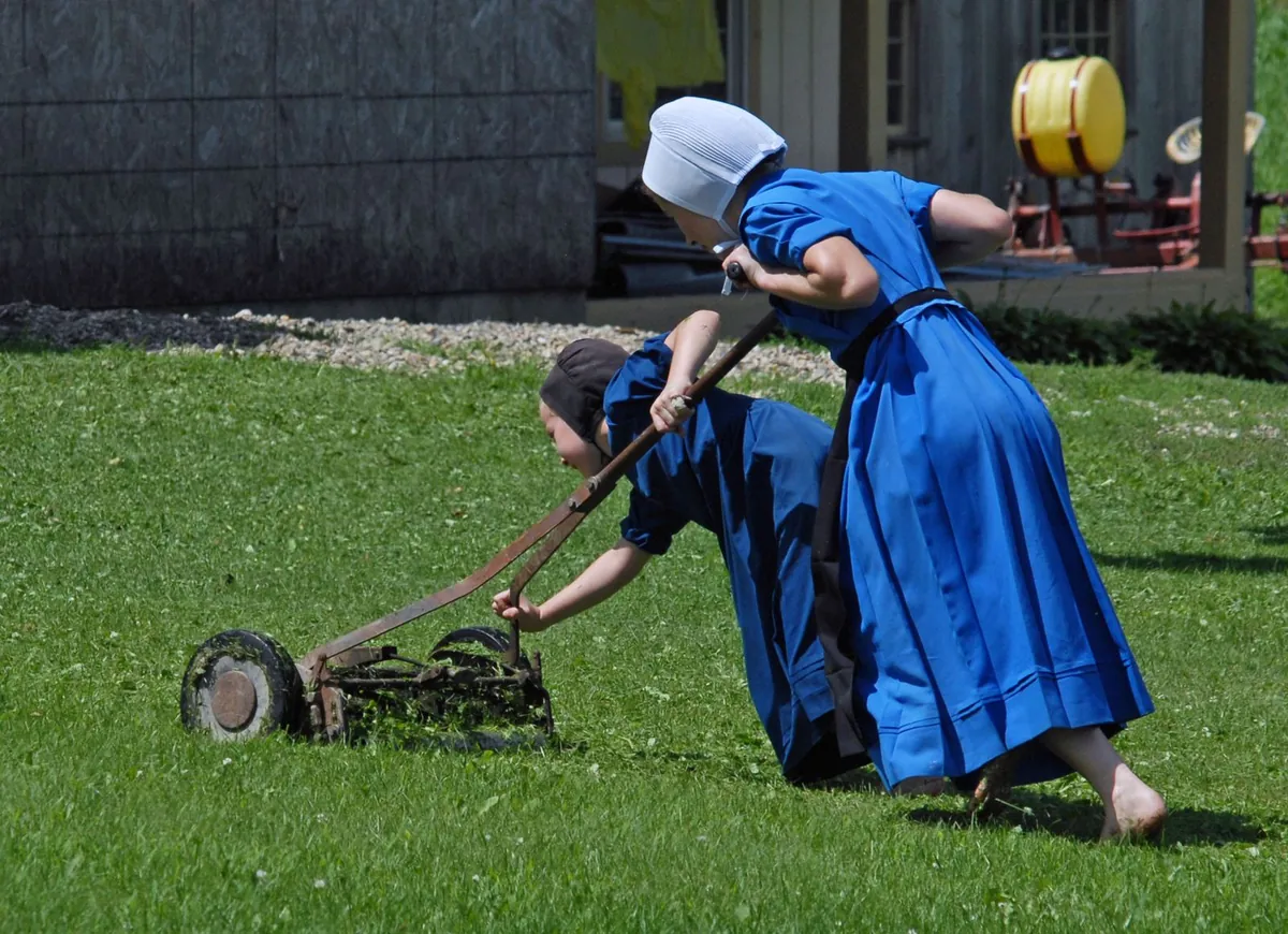 Amish women mowing a lawn with a manual reel mower