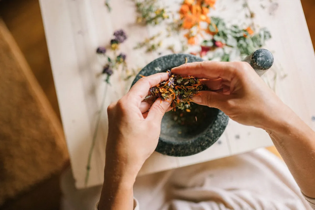 Hands mixing dried herbs in a mortar and pestle