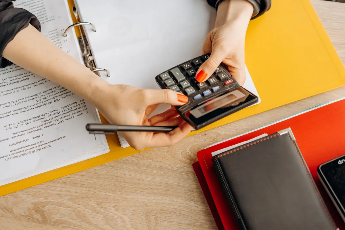 Hands using a calculator at a desk with financial documents