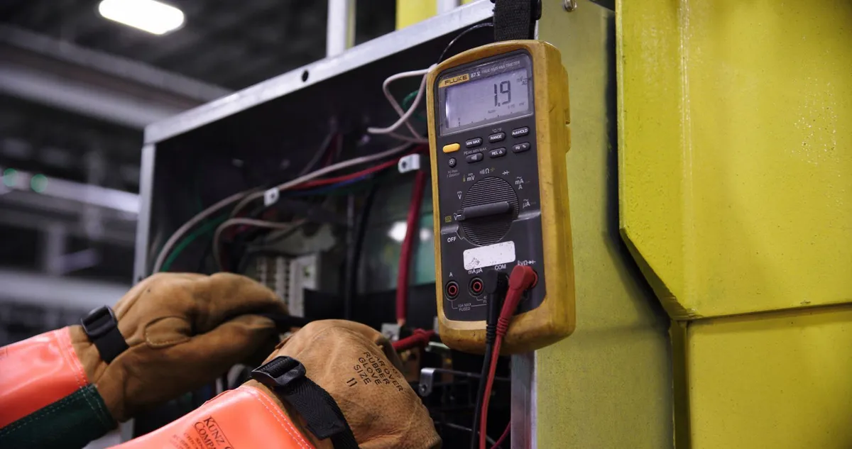 Electrician testing an industrial control panel with a multimeter